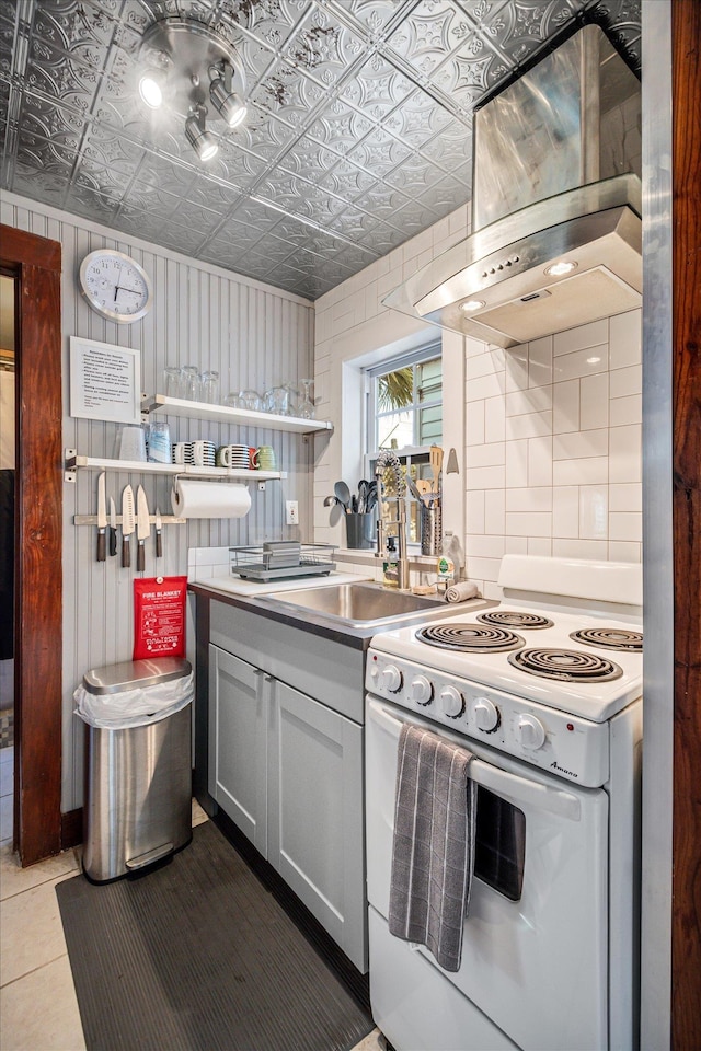 kitchen with an ornate ceiling, white electric range oven, tile patterned flooring, wall chimney exhaust hood, and extractor fan