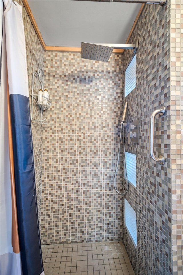 full bath featuring ornamental molding, a tile shower, and tile patterned floors