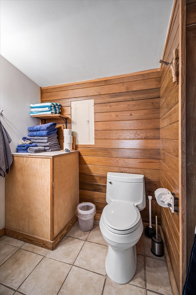 half bathroom with wood walls, tile patterned flooring, and toilet