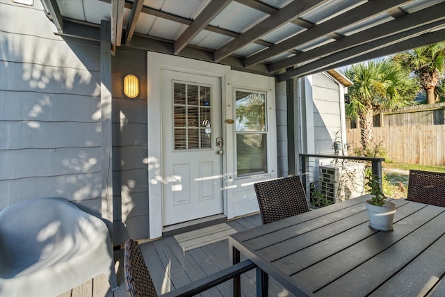 view of exterior entry with fence and outdoor dining space