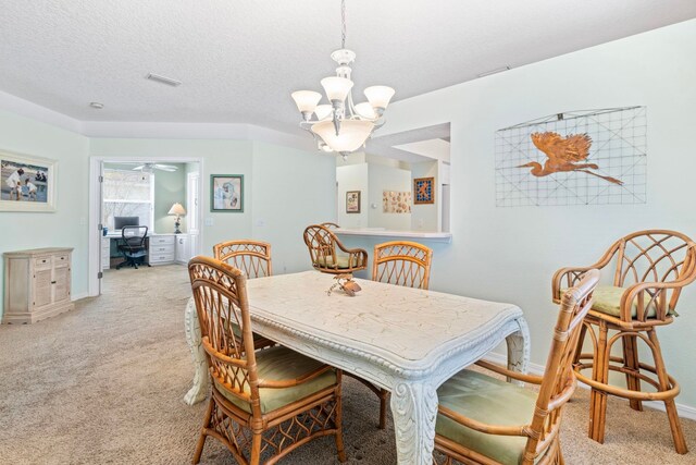 dining space with a textured ceiling, light colored carpet, visible vents, baseboards, and an inviting chandelier