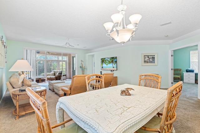 dining space with ceiling fan with notable chandelier, visible vents, a textured ceiling, and light colored carpet