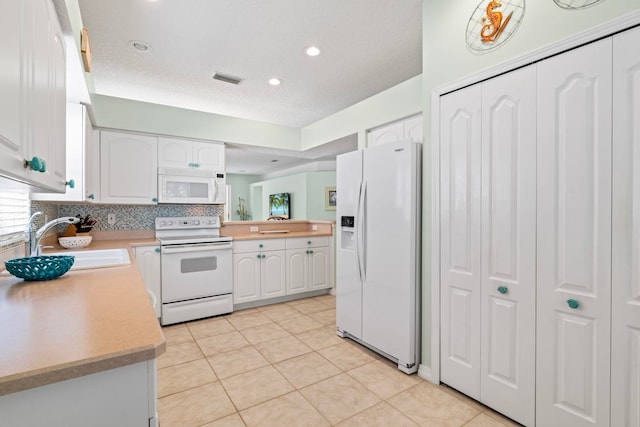 kitchen featuring white appliances, light countertops, a sink, and white cabinets