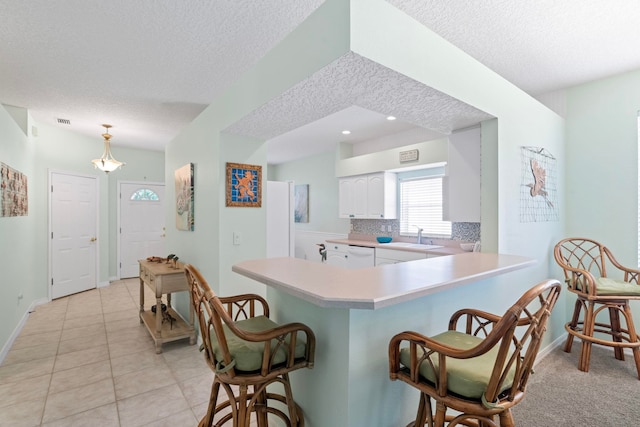 kitchen with white cabinets, light countertops, a sink, and a kitchen breakfast bar