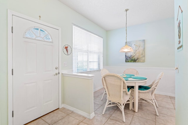 dining space featuring a textured ceiling, baseboards, and light tile patterned floors