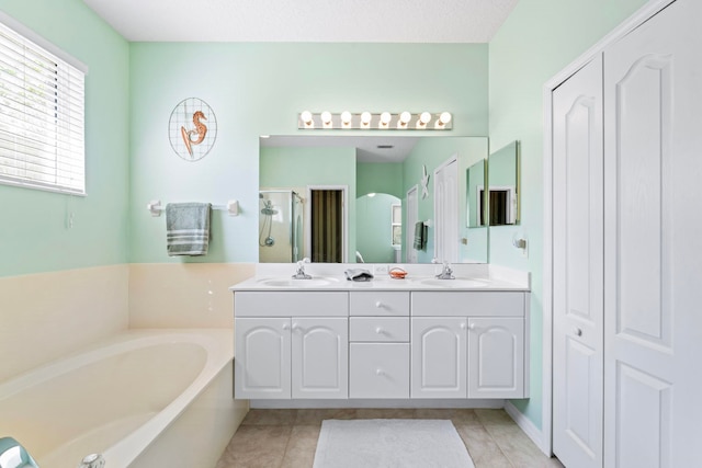 bathroom featuring tile patterned flooring, a sink, a bath, and a shower stall