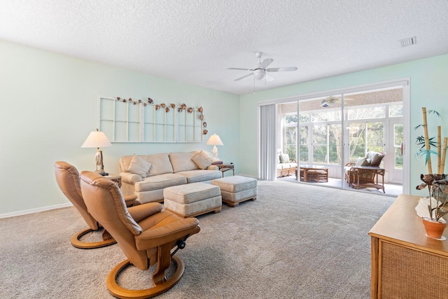 carpeted living room featuring ceiling fan, a textured ceiling, visible vents, and baseboards