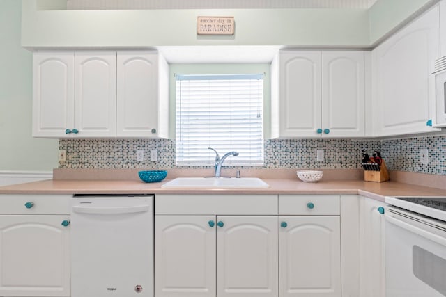 kitchen with white appliances, white cabinetry, decorative backsplash, and a sink