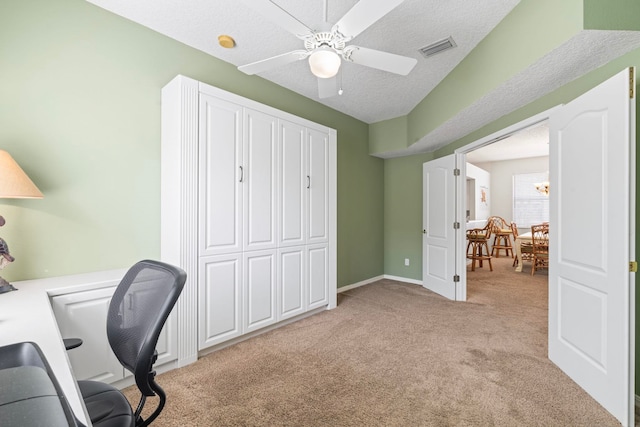 home office featuring a textured ceiling, light colored carpet, a ceiling fan, baseboards, and visible vents