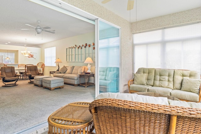 carpeted living room with ceiling fan with notable chandelier