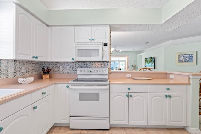 kitchen featuring a peninsula, white appliances, white cabinets, light countertops, and tasteful backsplash