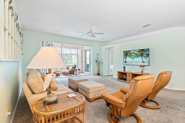 living room featuring a textured ceiling, a ceiling fan, visible vents, baseboards, and carpet