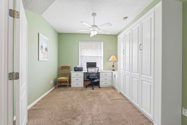 office space with light carpet, baseboards, a ceiling fan, and a textured ceiling