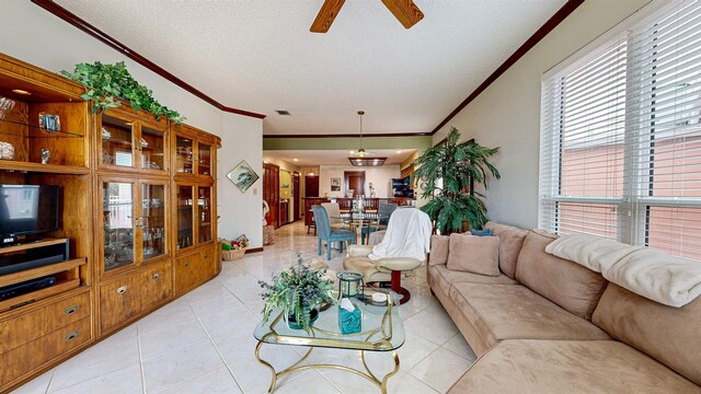 living room with light tile patterned flooring, crown molding, ceiling fan, and a textured ceiling