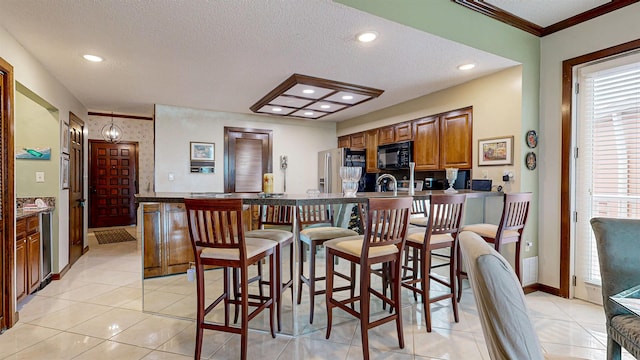 kitchen featuring stainless steel refrigerator with ice dispenser, black microwave, a kitchen bar, and light tile patterned flooring