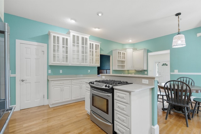 kitchen with pendant lighting, white cabinetry, stainless steel range with gas cooktop, and light hardwood / wood-style floors