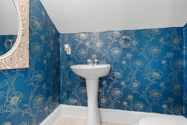 bathroom featuring tile patterned flooring, toilet, and a textured ceiling