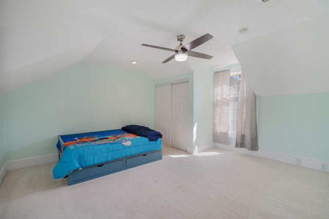 bedroom featuring ceiling fan, light colored carpet, lofted ceiling, and a closet