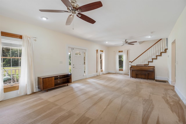 unfurnished living room featuring light carpet, ceiling fan, and a healthy amount of sunlight