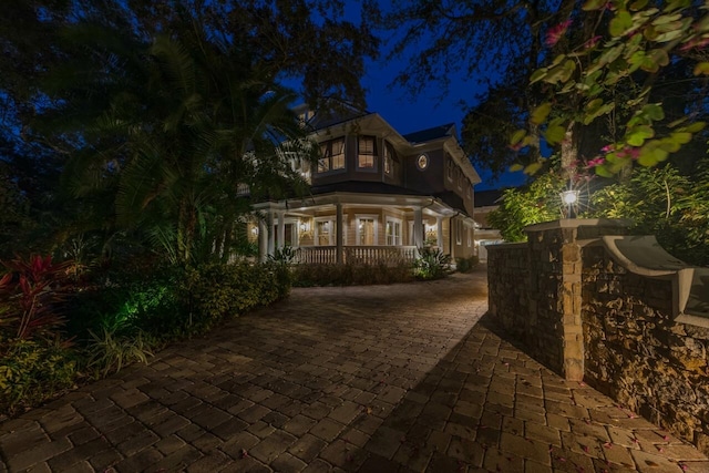 back of house at night featuring covered porch