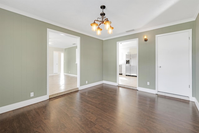 spare room featuring crown molding, hardwood / wood-style floors, and a chandelier