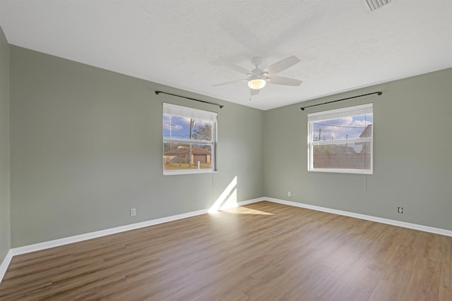 empty room with ceiling fan, wood-type flooring, and a textured ceiling