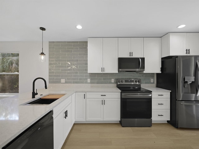 kitchen with white cabinetry, appliances with stainless steel finishes, decorative light fixtures, and sink