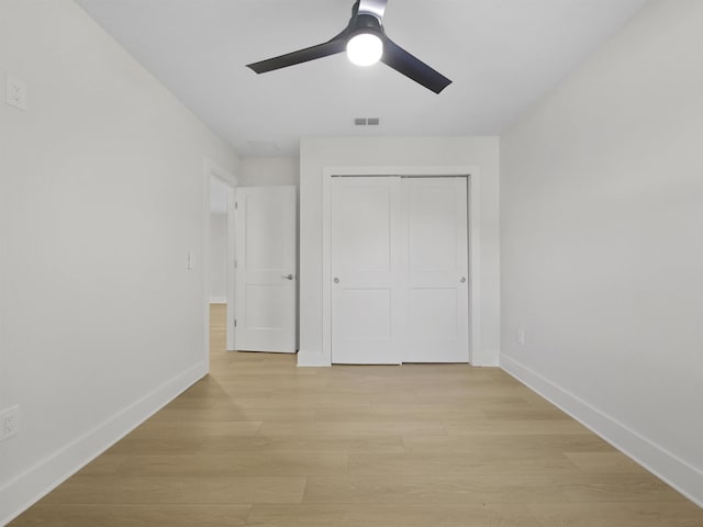 unfurnished bedroom featuring ceiling fan, a closet, and light wood-type flooring