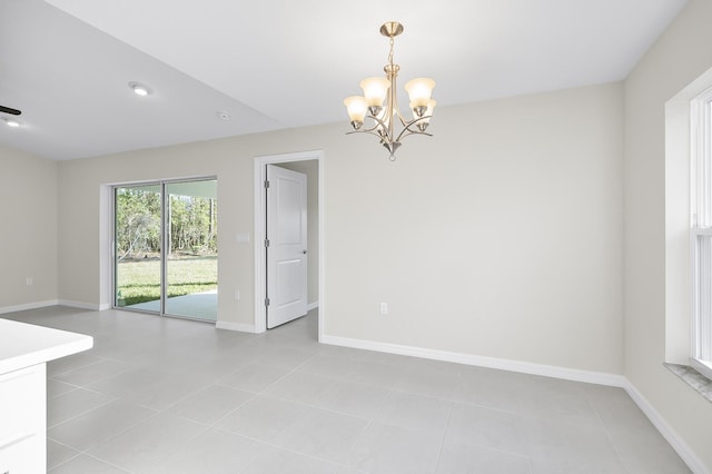 tiled spare room with a notable chandelier