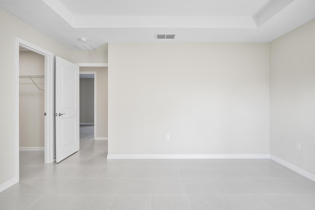 spare room featuring a raised ceiling and light tile patterned floors