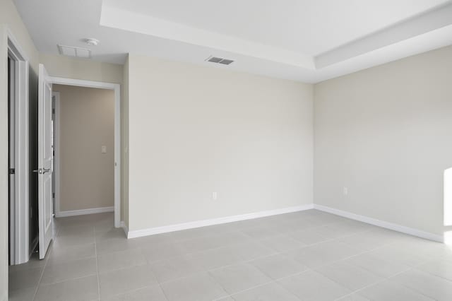 unfurnished room featuring a raised ceiling and light tile patterned floors