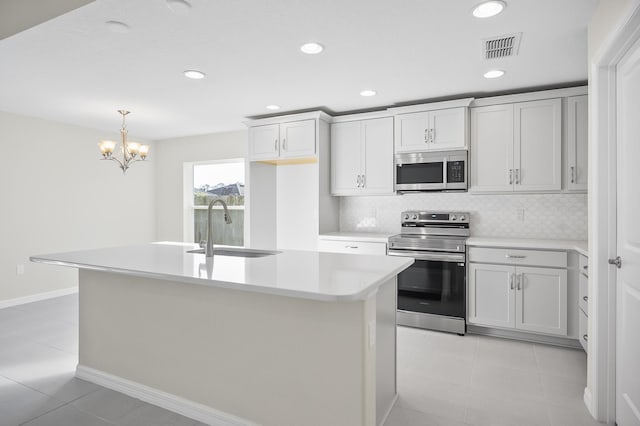 kitchen with tasteful backsplash, sink, a kitchen island with sink, light tile patterned floors, and stainless steel appliances