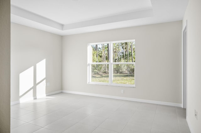 spare room with a tray ceiling and light tile patterned floors