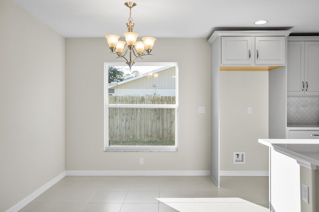 unfurnished dining area with light tile patterned floors and a notable chandelier