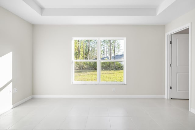 spare room with light tile patterned floors and a tray ceiling