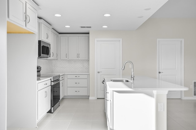 kitchen featuring sink, appliances with stainless steel finishes, white cabinetry, tasteful backsplash, and light tile patterned flooring