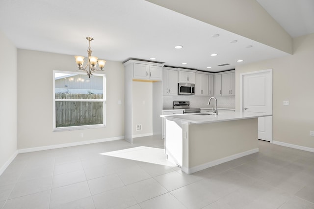 kitchen featuring pendant lighting, sink, a kitchen island with sink, stainless steel appliances, and a chandelier