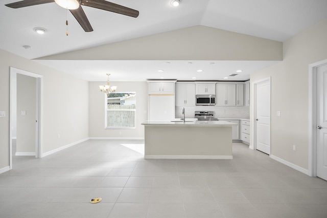 kitchen featuring light tile patterned floors, backsplash, stainless steel appliances, an island with sink, and vaulted ceiling