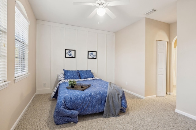 bedroom featuring carpet floors, arched walkways, visible vents, ceiling fan, and baseboards