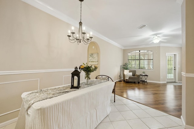 dining room with light tile patterned floors, baseboards, visible vents, crown molding, and ceiling fan with notable chandelier