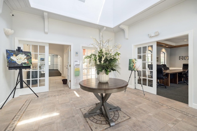 interior space with arched walkways, a towering ceiling, baseboards, french doors, and a wealth of natural light