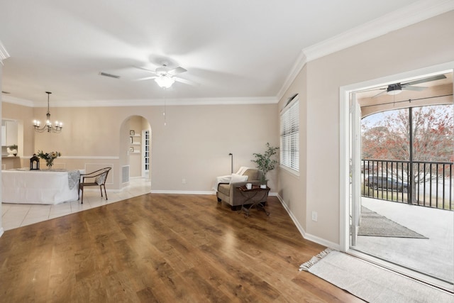 unfurnished room with visible vents, arched walkways, wood finished floors, crown molding, and ceiling fan with notable chandelier