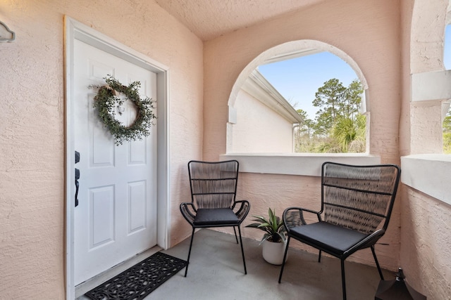 view of exterior entry with a balcony and stucco siding