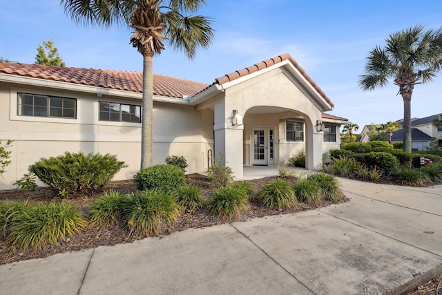 mediterranean / spanish-style home with french doors, a tiled roof, and stucco siding