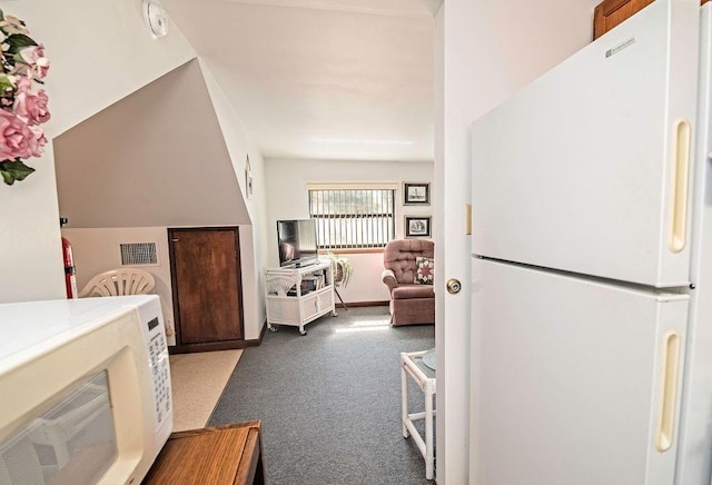 kitchen with lofted ceiling, dark carpet, and white appliances