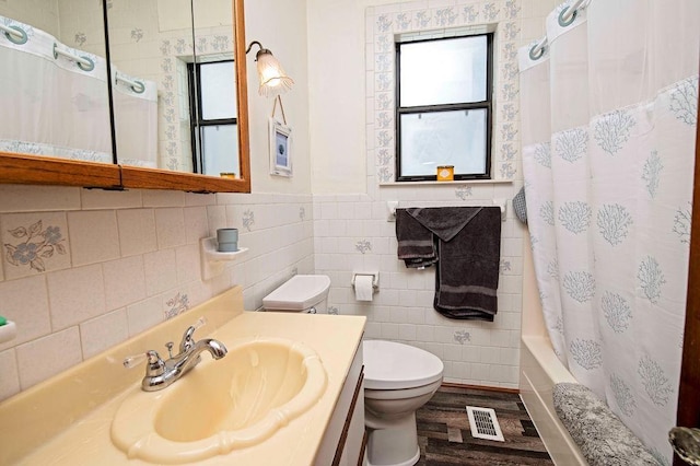 full bathroom featuring toilet, wood-type flooring, tile walls, and shower / tub combo with curtain