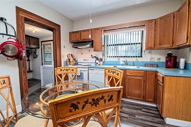 kitchen featuring white appliances, backsplash, sink, dark hardwood / wood-style floors, and washer / dryer