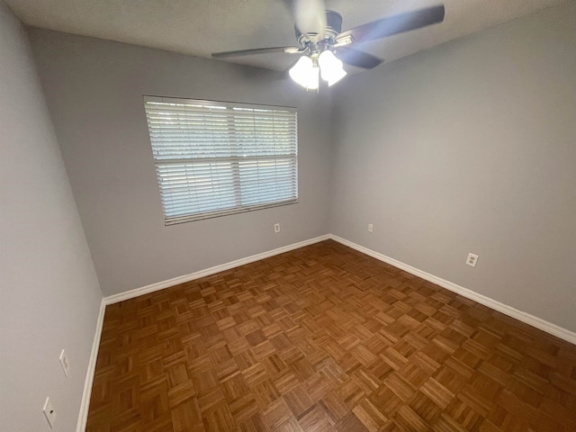 empty room with dark parquet floors and ceiling fan