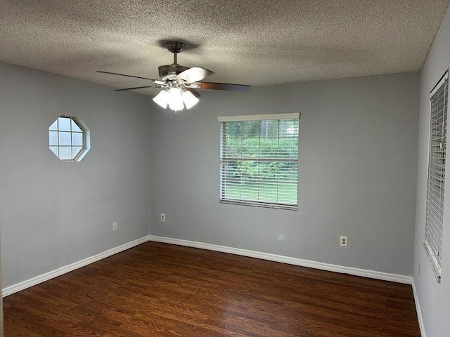 empty room featuring ceiling fan, dark wood-type flooring, and a textured ceiling