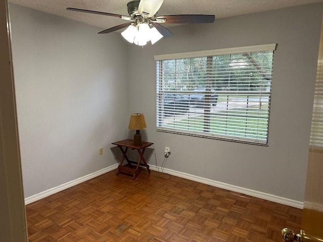 spare room featuring a textured ceiling, ceiling fan, and dark parquet floors